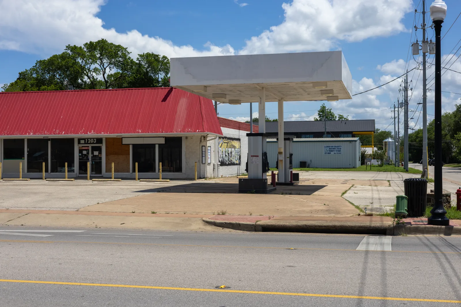 An abandoned and boarded-up gas station on a Bastrop road